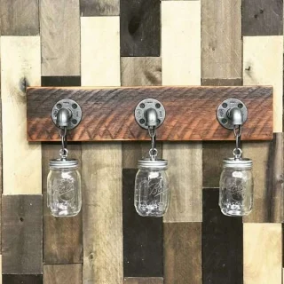 Handmade 3 light mason jar fixture with aged wood above bathroom mirror