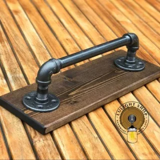 Rustic wood towel bar with industrial pipe hardware on bathroom wall