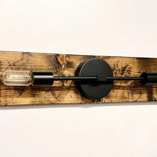 Handmade black metal and wood wall sconce above bathroom mirror
