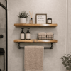wood floating shelves on a bathroom wall with a towel bar for hanging towels