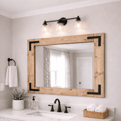 large walnut wood frame mirror hanging on a bathroom wall in a farmhouse bathroom with black hardware on cornets