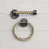 Coastal farmhouse rope bathroom set with towel ring and toilet paper holder on light gray wood background made of pipe and natural rope for bathroom